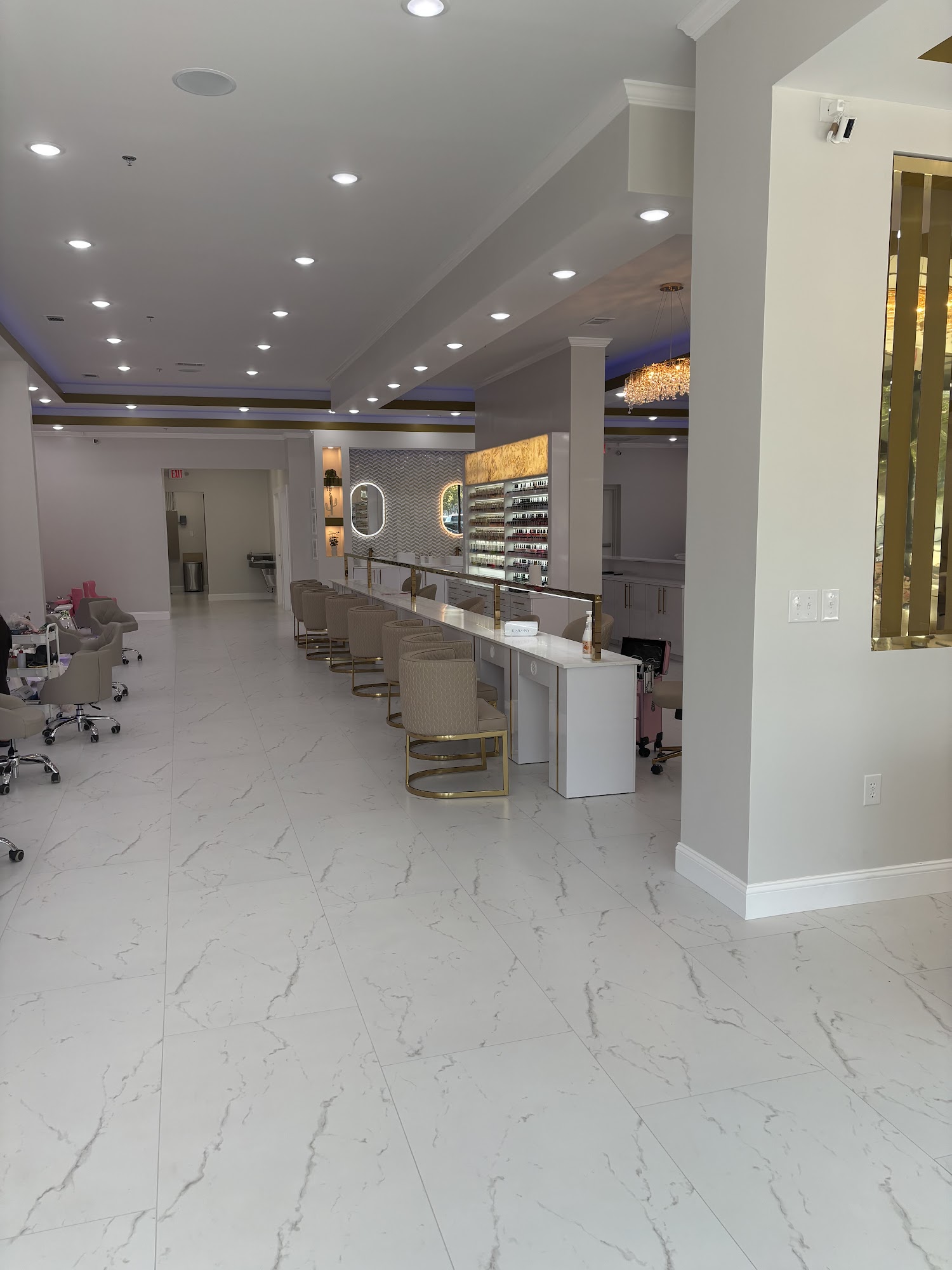 Manicure bar with gold-framed chairs and marble counters